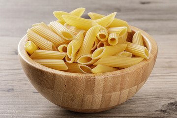 Raw Penne Rigate noodles isolated on a wooden background