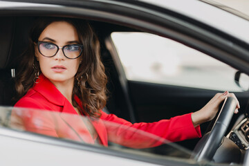 beautiful sexy rich business woman in red suit sitting in white car, wearing glasses