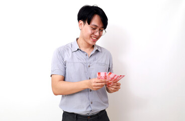 Happy asian man standing while holding Indonesian banknotes. Isolated on white