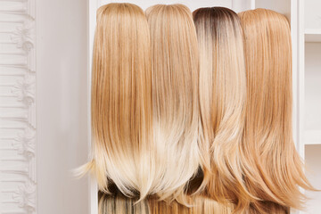Showcase of natural looking wigs in different shades of blonde fixed on the wig holders in beauty...