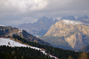A rocky mountain range surrounded by alpine forests with a snow-covered mountain peaks in the background