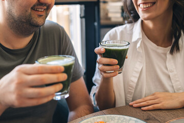 A young happy man and a woman are sitting in a cafe and drinking matcha tea,hands close-up.Healthy eating concept.