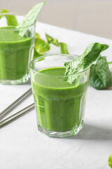 Healthy green smoothie with spinach, avocado, banana, and vegan milk in two glasses and fresh ingredients on light table