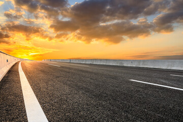 Fototapeta premium Asphalt highway and sky clouds background at sunset