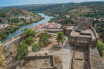 Walls and castle of Mértola in aerial view and Guadiana river between mountains, Alentejo PORTUGAL
