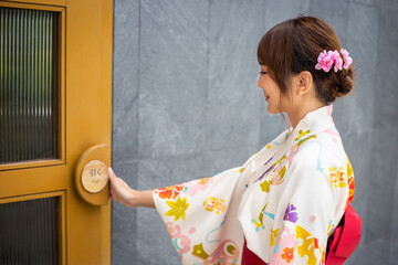 young woman wearing a Japanese traditional kimono is opening a door. select focus