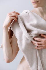 Smiling woman covering her body with a beige towel