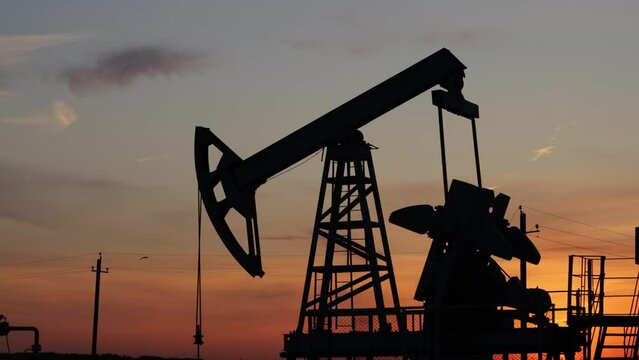 Silhouette of a working oil pump at sunset. Crude oil, industry. Oil field.