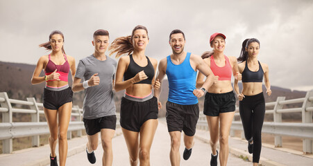 Group of people in sportswear running over a bridge