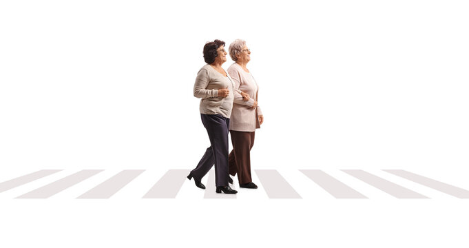 Full length profile shot of two elderly ladies walking at a pedestrian crossing