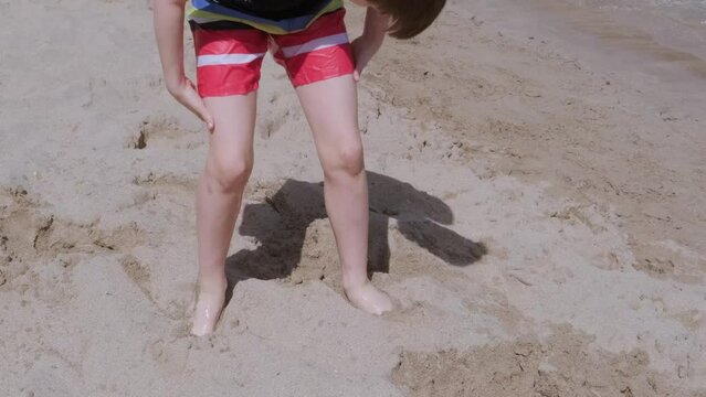 child on beach, healthy boy 9-10 years old fun playing with sand on shore, runs into water, sea, digs in feet, sand play, learning swimming skills, playing in water, wonderful vacation, improve health