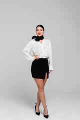 Fototapeta premium Portrait of an attractive young Stewardess. Charming, smiling air hostess in sensual uniform. Isolated on white background. Studio shoot.