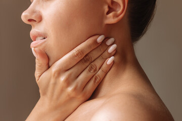 Inflamed tonsillar lymph nodes. Young woman touches enlarged lymph nodes under jaw on her neck with...