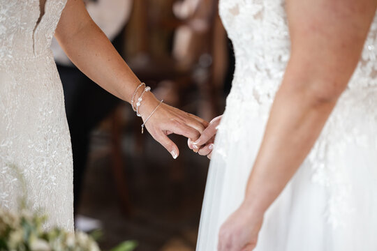 Beautiful two brides at same sex couple wedding ceremony holding hands in white dresses. Romantic, intimate and full of love.