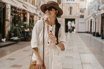 Obraz premium attractive woman walking in shopping street in Italy on vacation dressed in white summer fashion dress