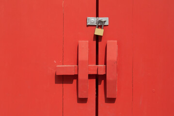 Golden padlock on old red wooden door