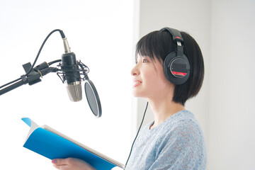 スタジオでナレーションをする女性のナレーター