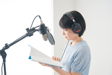 スタジオでナレーションをする女性のナレーター