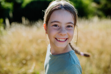 Portrait of a beautiful little girl laughing when having fun in summer in nature.