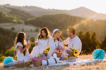 Happy family with children having picnic in nature.
