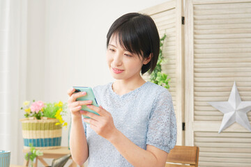 リビングでスマートフォンを使う女性