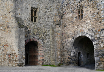 Fototapeta na wymiar Worn old stone walls of ruined medieval buildings with arch leading to dark passage