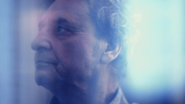 Brooding senior man lost in thought, gazing through his window as the world goes by. A contemplative older gentleman in his 70s with a stern expression, pondering the meaning of life