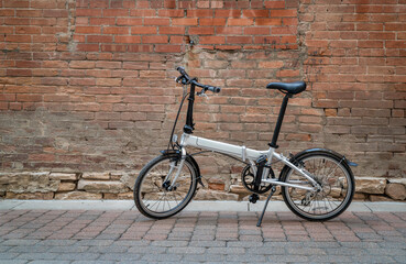 Fototapeta na wymiar lightweight folding bike in an alley against grunge brick wall