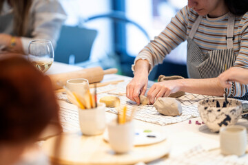 Crop women making clay cups during class together