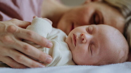 Mother cuddling with her newborn baby in their bed.