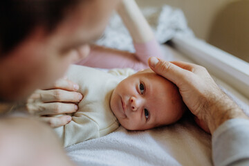 Close-up of parents cuddling their newborn baby.