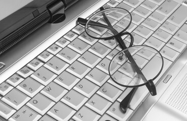 Round eyeglasses on silver laptop keyboard 