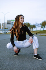 Portrait of a stylish teenage girl with dreadlocks on city street.