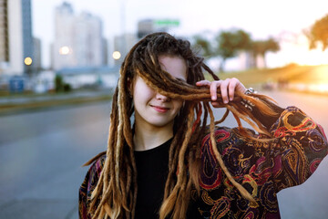 Portrait of a stylish teenage girl with dreadlocks on city street.