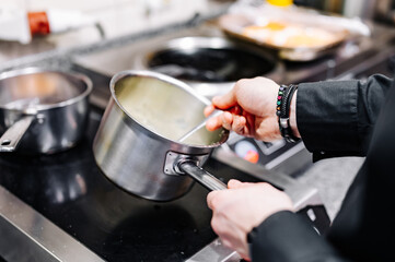 Chef hands cooking cheese sauce in the restaurant kitchen