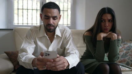 Boyfriend telling to girlfriend to wait while he browses internet on smartphone device. Arab couple in crisis. Female partnet feeling loneliness because of technology, alone together