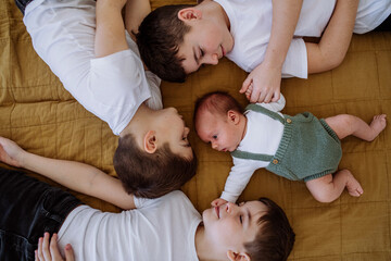 Three big brothers with their little newborn brother lying in bed.