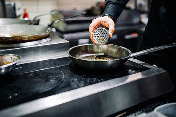 man chef cooking fried sesame in frying pan on kitchen