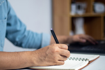 Male hand writing a note in a notebook concept of business people working