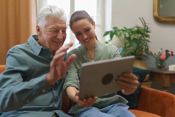 Senior man with his granddaughter using digital tablet.