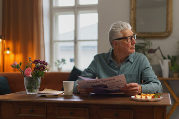 Senior man reading newspaper in his apartment.