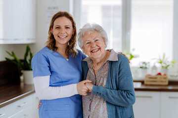Young nurse hugging her senior woman client.