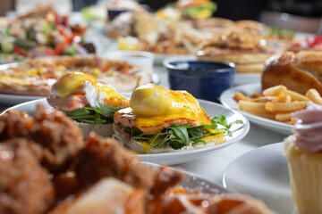 A view of a table full of assorted restaurant dishes, featuring eggs Benedict.