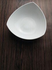 Hand hold white porcelain bowl on a wooden table. Top view. copy space