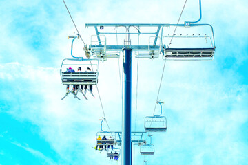 Skiers Riding Chairlift Isolated against Blue Sky