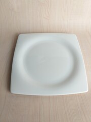 Empty white plate on wooden table. Top view with copy space.