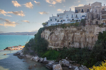 Fototapeta na wymiar A view of a cliff with houses on it and the sea in the background. Vieste, Puglia, Italy.