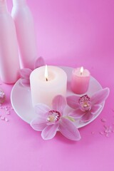 Obraz na płótnie Canvas Fresh pink orchid flowers, burning candles, sea salt, on a bright pink background