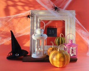 Halloween, a lantern with a burning candle, pumpkins, a witch's hat, against the background of a frame, cobwebs with spiders and magical shadows, the concept of interior decoration for the holiday
