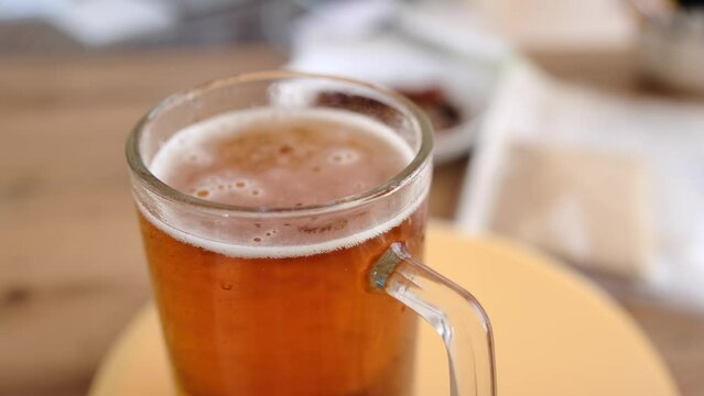 Close-up glass of cold beer on the table. Glass full light craft beer spin with drop of condensation cold drink. Cold alcohol beer drink in mug. Drink glass on table. 